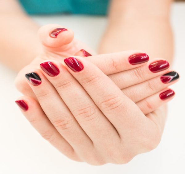 Closeup photo of a beautiful female hands with red nails on white background