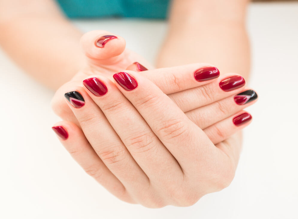 Closeup photo of a beautiful female hands with red nails on white background